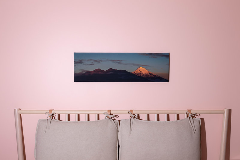 A wider view of a canvas print hung above a bed